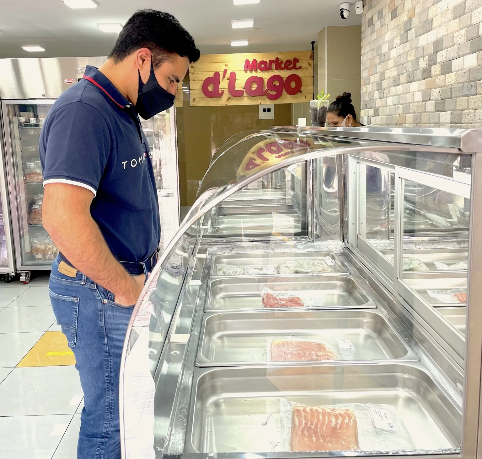 Cliente eligiendo cortes en la vitrina refrigerada de una sucursal Market d'Lago