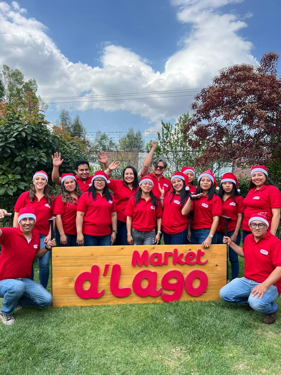 Equipo de Market d'Lago reunido alrededor del letrero de la marca
